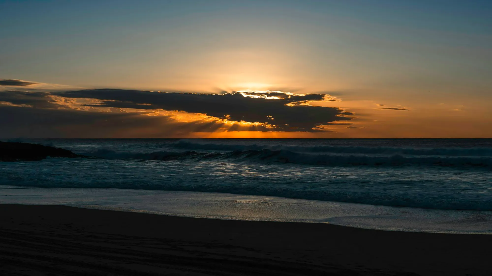 El sol asomando entre las nubes sobre el mar