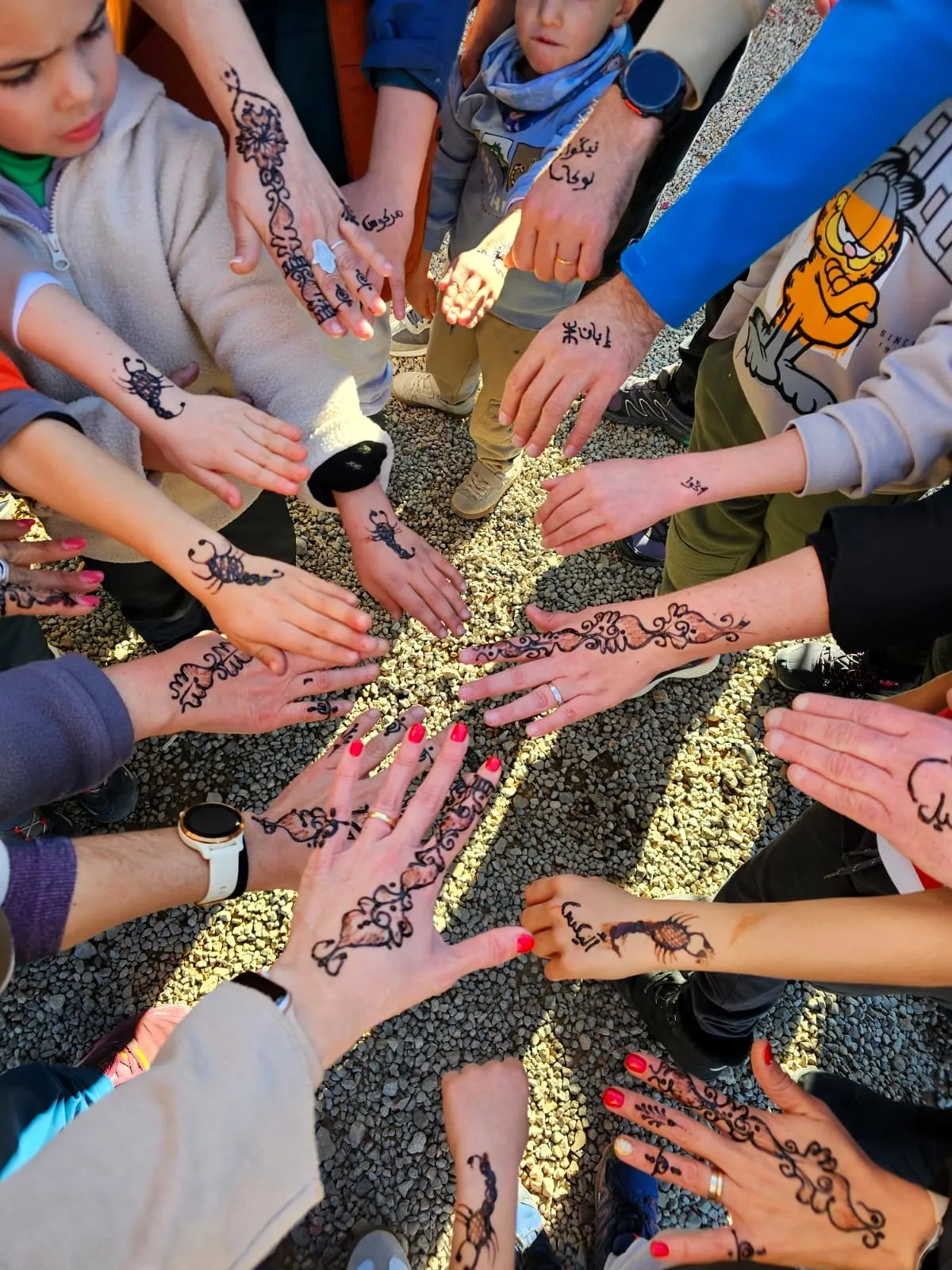 Manos de niños y adultos decoradas con henna, en el viaje de otro año