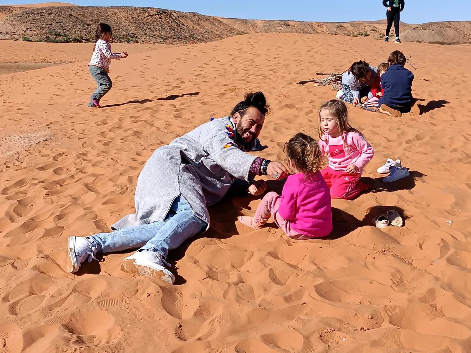 Jugando con las niñas en la arena del desierto, en el viaje de otro año